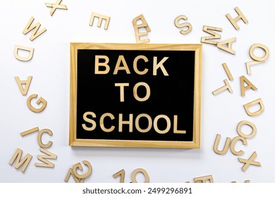 Black school blackboard with "Back to School" inscription in wooden letters. Scattered letters side by side. Top view. For backgrounds and presentations - Powered by Shutterstock