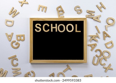 Black school blackboard with "School" inscription in wooden letters. Scattered letters side by side. Top view. For backgrounds and presentations - Powered by Shutterstock