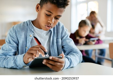 Black schoolboy e-learning on digital tablet during a class in the classroom. - Powered by Shutterstock