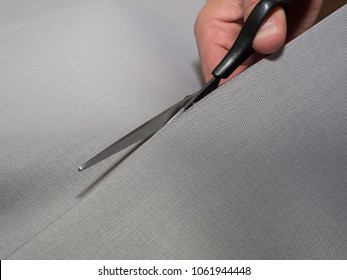 Black scissors cutting fabric. Concept of textile cutting-out. Close-up