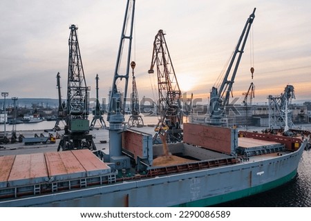 Black Sea Grain Initiative 2023 grain Deal. Silhouettes of port cranes during the loading of grain on a bulk carrier at sunset during the golden hour. Panoramic flight from a drone