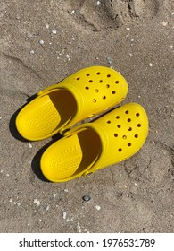 Black Sea, Ukraine - May, 2021: Yellow Beach Crocs On The Sand From The Top. Summer Footwear. Croc Shoes.