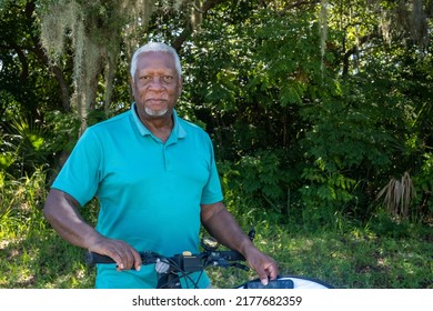 Black Senior Citizen Bicycling For Daily Exercise In A Blue Polo Shirt.