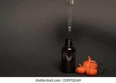 A Black Serum Bottle On A Black Background With Plasticine Pumpkins And A Spider , A Creative Halloween Concept