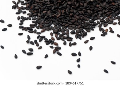 Black Sesame Seeds Scattered On White Background.