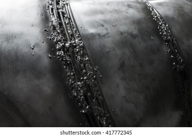 Black shining metal surface with weld seam elements, closeup photo with selective focus