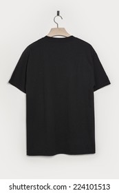 A Black Shirt Back Side With Wooden Hanger Isolated White.