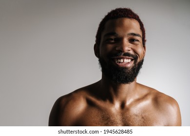 Black shirtless bearded man smiling and looking at camera isolated over white background