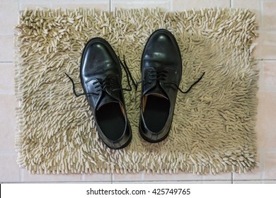 Black Shoes Put On A Foot Scraper. Somebody Take Off Shoe And Go To House For Relax, Resting Or Sleeping With Lovely Family.