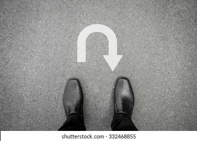 black shoes standing on the asphalt concrete floor in front of u turn symbol