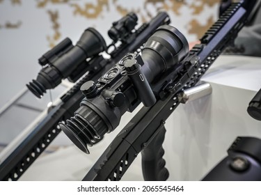 Black Shooting Scope Optics Mounted On Metal Bar Displayed At Weapons Exhibition Fair, Closeup Detail To Adjustment Knobs