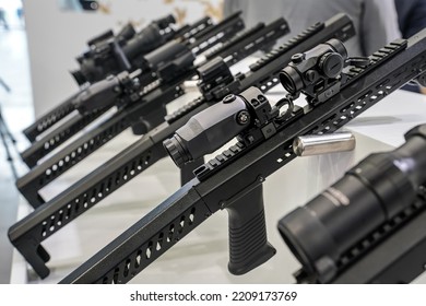 Black Shooting Scope Optics Mounted On Metal Bar Displayed At Weapons Exhibition Fair, Closeup Detail To Adjustment Knobs