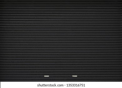 black shutter door with stainless steel holder. grunge black metal foldable door background and texture.