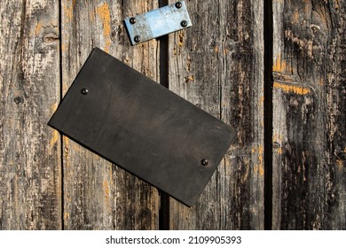 Black Sign With Space For Text, On A Wooden Plank Door In A Rural Setting