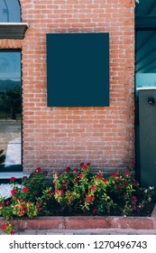 Black Signage Board On The Brick Wall Top Of The Flower Pot At Outdoor. Nameplate On Brick Wall At The Garden. Black Signage On A Brick Wall Mockup