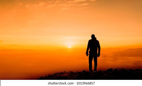 Black Silhouette Of Man On Sunset Above The Clouds