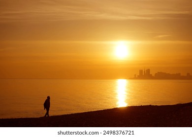 black Silhouette of man walking at the beach. one male walking. walk at sunset. human Walking  on coastline at sunset. sunray. Batumi Georgia - Powered by Shutterstock