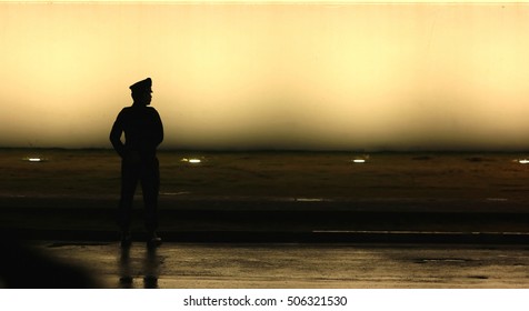 Black Silhouette On Wall Background Of A Uniformed Police Officer, Style Photo Blur