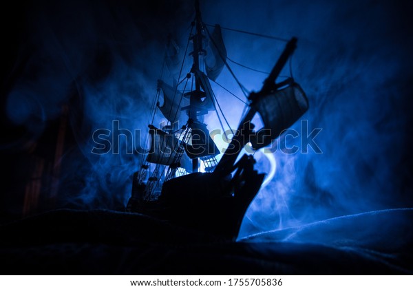 Black silhouette of the pirate ship in night. night\
scene of ghost pirate ship in the sea with mysterious light.\
Selective focus