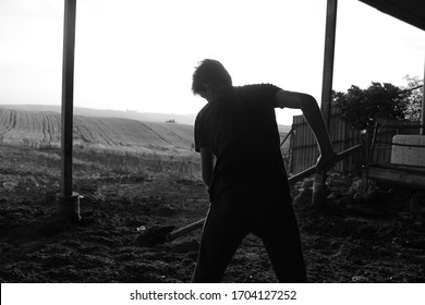 Black Silhouette Of A Worker Man Digging Soil With Shovel On Sun Light