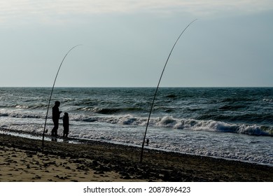 Black Silhouettes Of Father And Son With Fishing Rods By The Sea