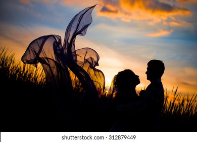 Black silhouettes men   women against the background beautiful sunset  love  dating  kiss  the dress  looks like butterfly wings