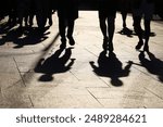 Black silhouettes and shadows of people on the street. Crowd walking down on sidewalk, concept of pedestrians, crime, society, city life