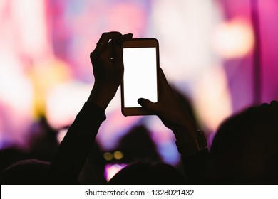 Black Silhoutte Of Music Fan With Smartphone On Dance Floor Filming Video And Taking Pictures On Popular Edm Musical Festival In Nightclub.Empty White Mobile Phone Screen To Place Event Logo