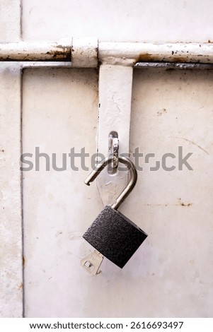 A black and silver padlock hangs from the latch of an old, vintage door, showcasing the charm of aged metal and classic security hardware. Perfect for themes of nostalgia, history,