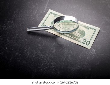 Black Slate Background With Antique Silver Magnifying Glass Perched On It's Edge With Light Streaming Through And Studio Lighting