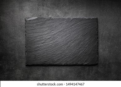 Placa de ardósia preta na vista superior da textura de pedra escura. Espaço vazio para menu ou receita.