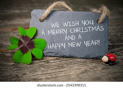 Black slate plate with four leaf clover and with the german words for Merry Christmas and happy new year - Frohe Weihnachten und ein frohes neues jahr 2025 on wooden weathered background	 - Powered by Shutterstock