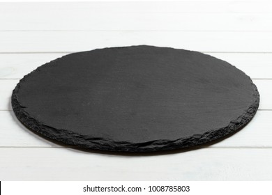 Black slate round stone on wooden background, top view, copy space. - Shutterstock ID 1008785803