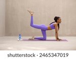 Black slim lady doing donkey kicks exercise with leg raise, training on yoga mat during outdoors workout, side view, free space