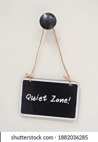 Black Small Chalkboard Hanging On White Bacjground With Text Handwritten Quiet Zone, Concept Of An Area In Coworking Space Or Library Or Office Which Need Silence , Or An Introvert Need Privacy