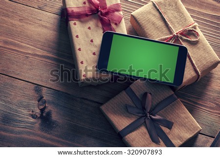 Black smart phone on a heap of gift boxes. Clipping path included.