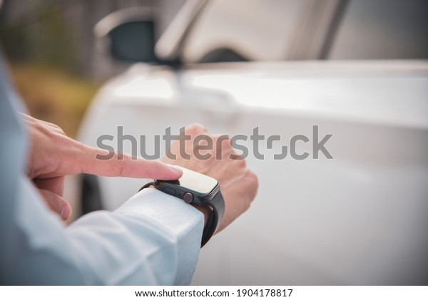 black smart watch on the\
business man\'s wrist with white car blurry background, technology\
concept
