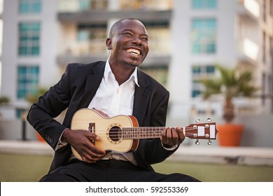 Black Smiling Man Wearing Formals Playing A Guitar