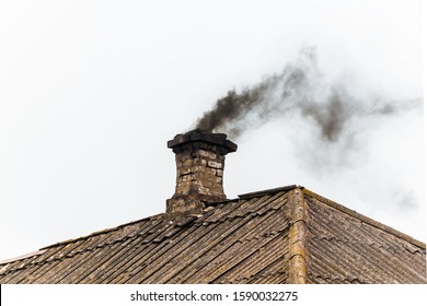 Black Smoke From The Chimney Of An Apartment Building During Heating And Heating On The Roof Of Slate.