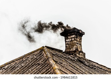 Black Smoke From The Chimney Of An Apartment Building During Heating And Heating On The Roof Of Slate.