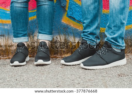 Black sneakers on couple's legs on the graffiti background