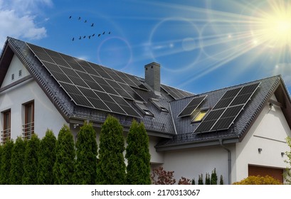 Black solar panels on gable roof. Beautiful, large modern house and solar energy. Rays of sun. - Shutterstock ID 2170313067