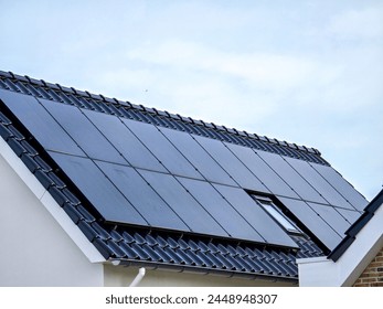 black solar panels on the roof against a sunny sky Close up of new house with black solar panels. Zonnepanelen, Zonne energie, Translation: Solar panel, Sun Energy, Suburban area - Powered by Shutterstock