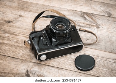 Black Soviet film camera in a leather case on a wooden unpainted surface with knots. - Powered by Shutterstock