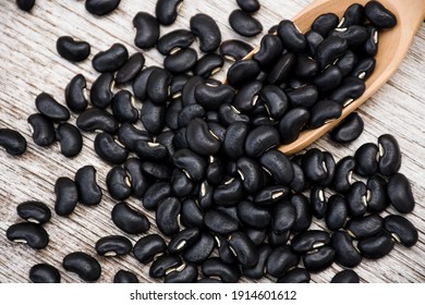Black soy beans ( Urad dal, black gram, vigna mungo ) in wooden scoop isolated on wood table background.
