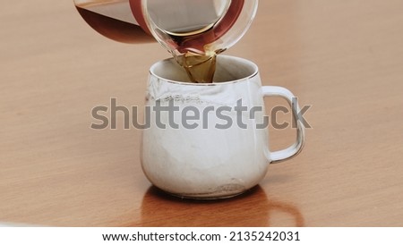Black specialty coffee being served in mug on wooden table