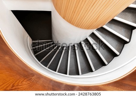 Black spiral staircase goes down in wooden interior, top view, abstract architecture photo background