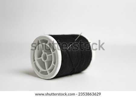 Black spool thread needle isolated on white background
