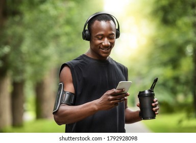 Black sportsman chatting with friends on mobile phone during break, exercising at public park - Powered by Shutterstock