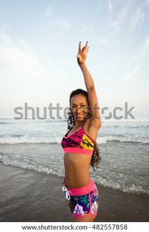 Black sporty woman dancing at the beach. Young happy brazilian dancer training against the sea.